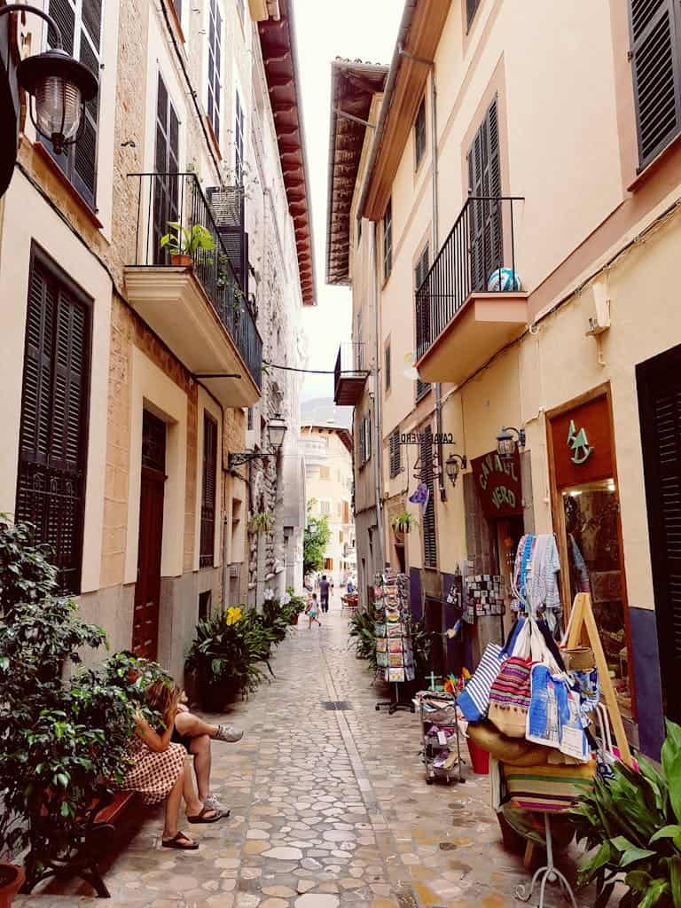 Explore a picturesque narrow street in Madrid lined with quaint shops and balconies.