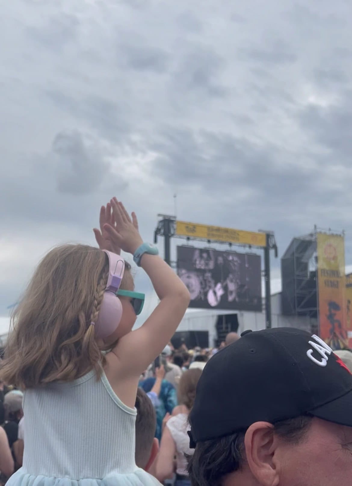 young girl with pink headphones dancing at outdoor music festival.